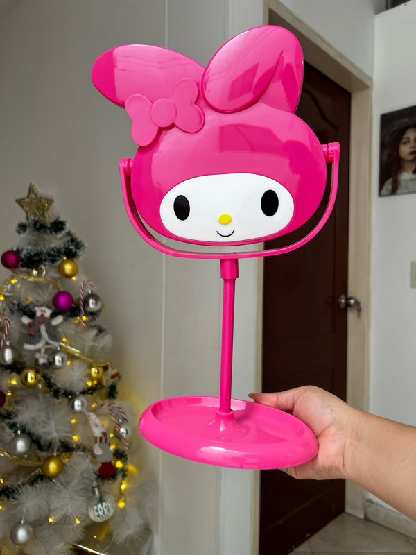 Espejo de mesa color rosa con forma de My Melody y base organizadora sostenido por una mano.